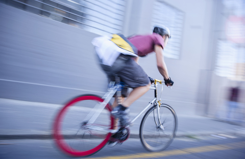 Fahrradkurier, der eine städtische Straße entlangrast, lizenzfreies Stockfoto