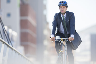 Geschäftsmann in Anzug und Helm fährt Fahrrad in der Stadt - CAIF12182