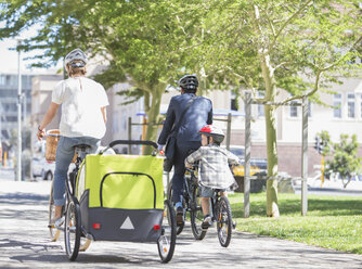 Familien auf Fahrrädern in einem sonnigen Stadtpark - CAIF12191