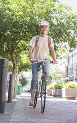 Junge Frau mit Helm auf dem Fahrrad in einem Stadtpark - CAIF12197