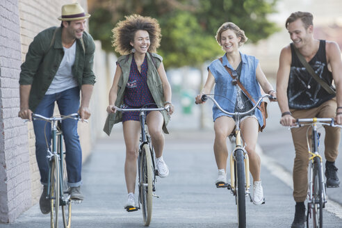 Freunde fahren mit dem Fahrrad auf einem städtischen Bürgersteig - CAIF12207