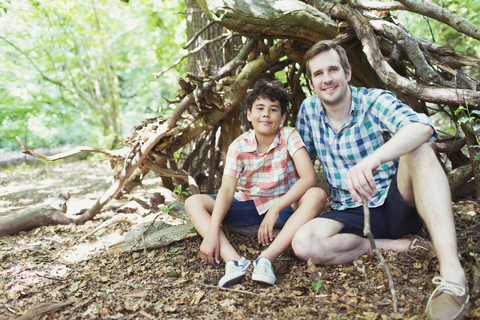 Portrait lächelnder Vater und Sohn im Wald, lizenzfreies Stockfoto