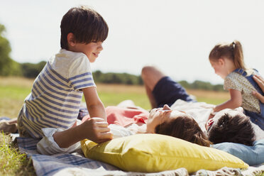 Family relaxing on blanket in sunny field - CAIF12300