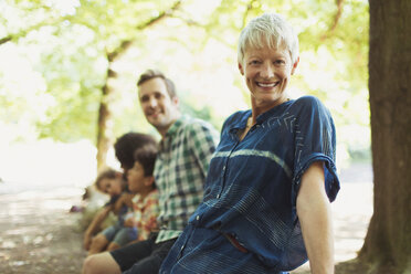 Portrait lächelnde Mehrgenerationenfamilie im Wald - CAIF12304