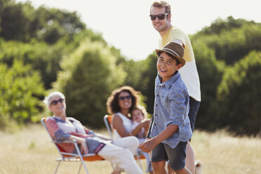 Portrait playful son pulling father in sunny field - CAIF12311