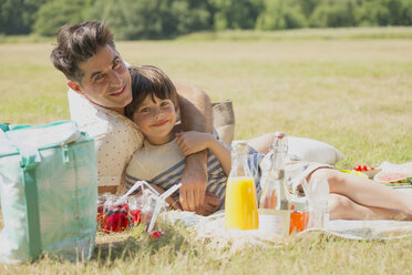 Portrait liebevoller Vater und Sohn entspannen sich auf einer Picknickdecke in einem sonnigen Feld - CAIF12315
