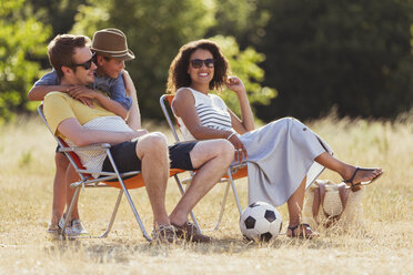 Lächelnde Familie entspannt sich auf einem sonnigen Feld - CAIF12320