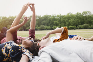 Freunde nehmen Selfie im Kreis im Gras liegend - CAIF12325