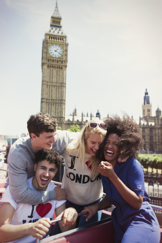 Begeisterte Freunde fahren mit dem Doppeldeckerbus unter dem Uhrturm Big Ben, London, Vereinigtes Königreich, lizenzfreies Stockfoto