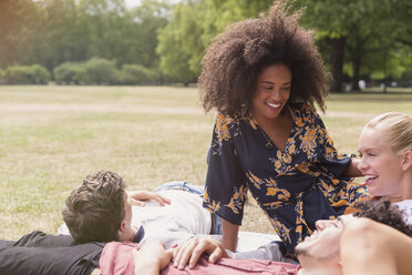 Friends hanging out relaxing on blanket in park - CAIF12337