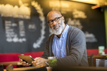 Portrait of man with tablet in a coffee shop - FMKF04906