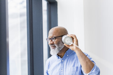 Businessman using tin can phone - FMKF04923