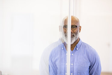 Portrait of bald businessman and his mirror image on glass pane - FMKF04933