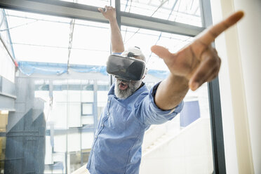 Businessman wearing VR glasses at the window - FMKF04963