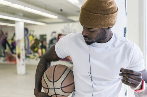 Mann mit Basketball, Wollmütze und Kopfhörern - UUF12982