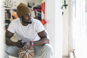 Smiling man with basketball, smartphone and earphones - UUF12983