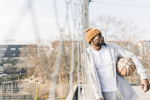 Basketballspieler auf dem Platz, der sich gegen den Zaun lehnt - UUF13006