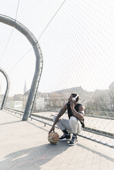 Basketball player on court crouching at fence listening to music - UUF13019