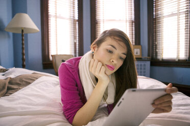 Frau benutzt Tablet-Computer, während sie zu Hause auf dem Bett liegt - CAVF05595