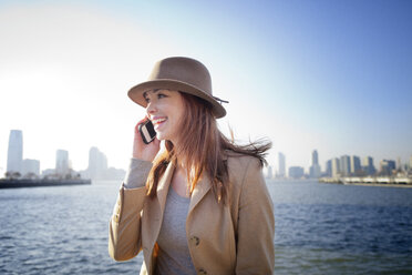 Frau spricht mit Handy am Fluss in der Stadt - CAVF05601