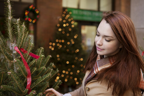 Frau kauft in einem Geschäft einen Weihnachtsbaum - CAVF05607