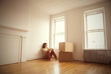 Frau schaut weg, während sie im neuen Haus auf dem Boden sitzt - CAVF05611