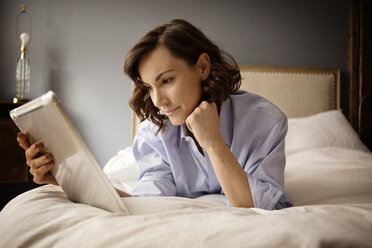 Frau benutzt Tablet-Computer, während sie zu Hause auf dem Bett liegt - CAVF05624