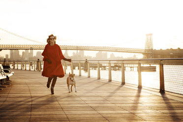 Frau läuft mit Hund auf Promenade gegen Williamsburg Bridge - CAVF05639