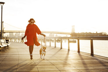 Frau mit Hund läuft auf Promenade gegen Williamsburg Bridge - CAVF05640