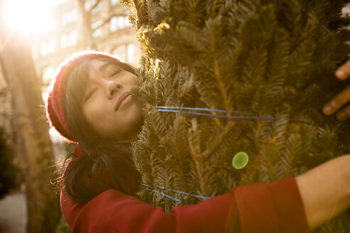 Woman hugging tied up Christmas tree - CAVF05648