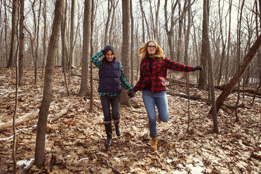 Friends holding hands while running in forest - CAVF05711