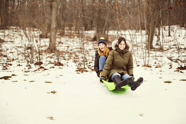 Cheerful friends on toboggan in forest - CAVF05740