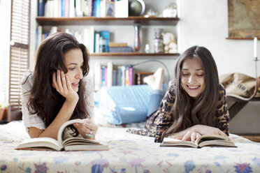 Woman looking at sister reading book - CAVF05754