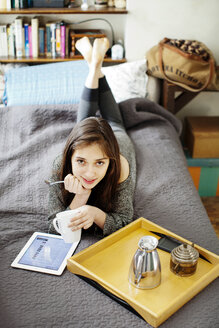 Porträt einer Frau mit Tablet-Computer auf dem Bett liegend - CAVF05773