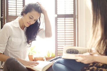 Geschwister lesen Bücher, während sie auf dem Bett sitzen - CAVF05782