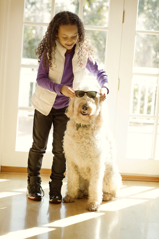 Glückliches Mädchen mit Sonnenbrille zum Hund, lizenzfreies Stockfoto