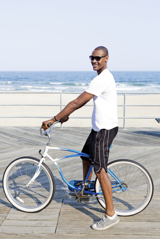 Mann mit Fahrrad auf der Seebrücke am Strand stehend, lizenzfreies Stockfoto