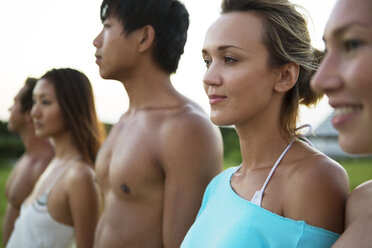 Friends looking away while standing side by side against sky - CAVF05894