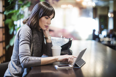 Frau, die in einem Restaurant auf einen Tablet-Computer schaut - CAVF05939