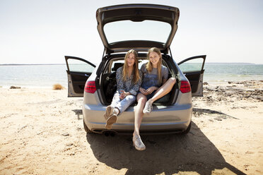 Freunde sitzen im Kofferraum eines Autos am Strand - CAVF05984