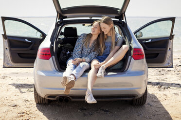 Freunde entspannen sich im Kofferraum eines Autos am Strand - CAVF05985