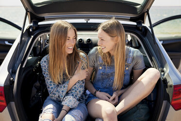 Happy friends sitting in car trunk - CAVF05986