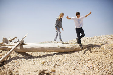 Couple jumping from log against clear sky - CAVF05999