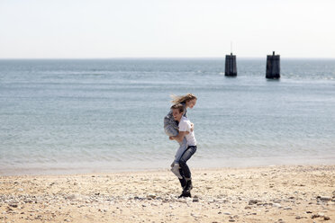 Man lifting girlfriend while standing on shore beach - CAVF06002