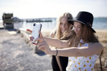 Friends taking selfie while standing against beach - CAVF06024