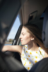 Frau schaut während der Fahrt durch ein Autofenster - CAVF06040