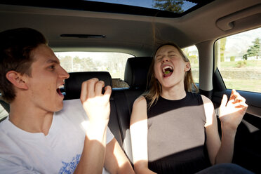 Verspielter Mann wirft Toffee in den Mund eines Freundes, während er im Auto unterwegs ist - CAVF06041