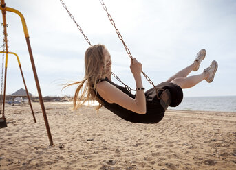 Side view of woman playing on swing against sky - CAVF06043