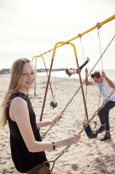 Portrait of woman playing swing at beach - CAVF06044