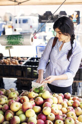 Frau kauft Äpfel an einem Marktstand - CAVF06054